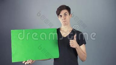 穿着黑色衬衫的年轻人拿着绿色钥匙片<strong>海报</strong>，<strong>灰色背景</strong>